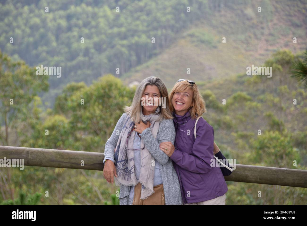 The two Caucasian women smiling and posing for a photo in the nature Stock Photo