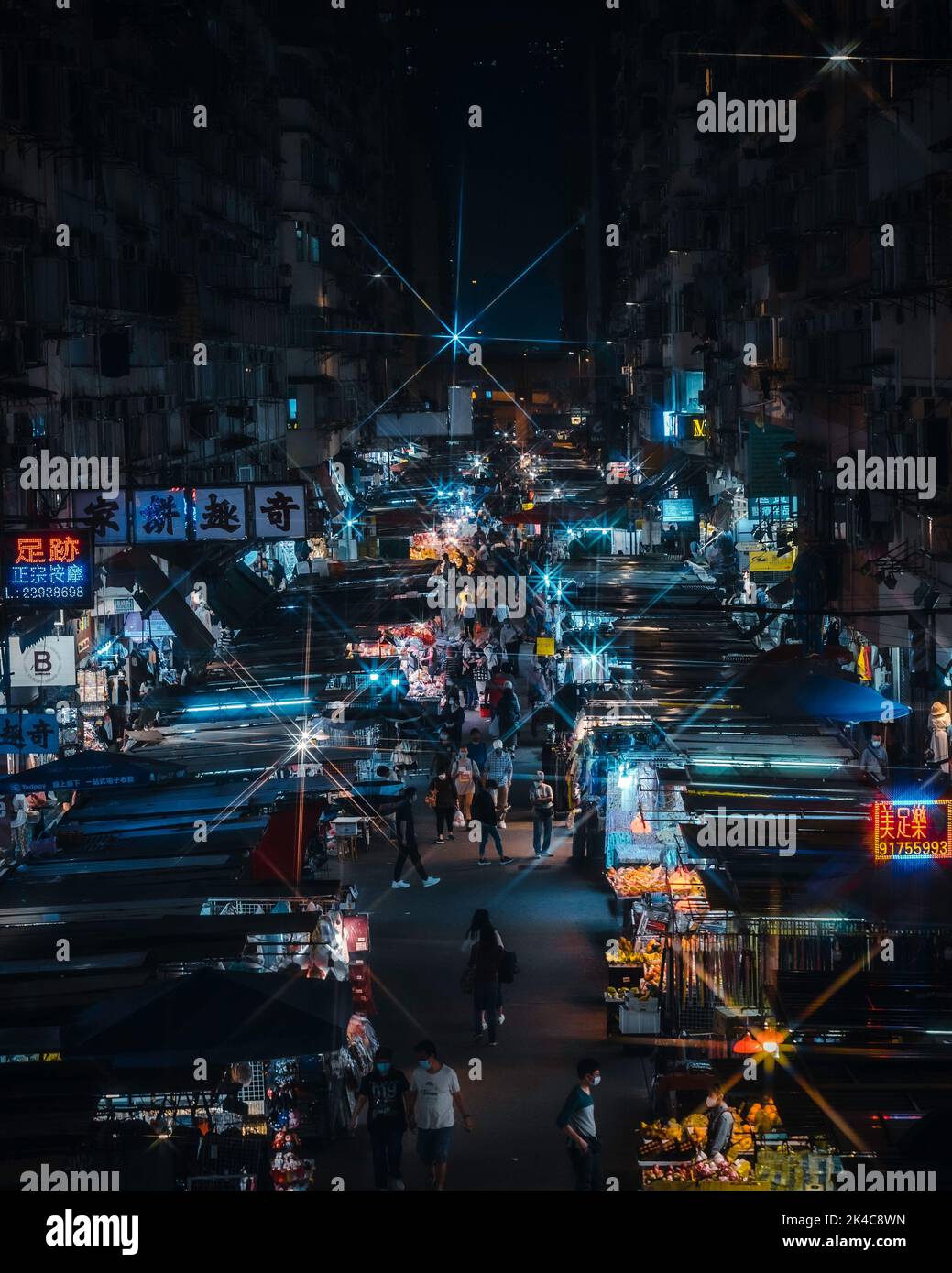 A vertical shot of a night street with a market and people Stock Photo