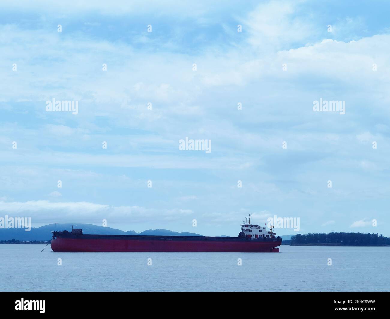 A big cargo ship on the calm ocean transporting supplies Stock Photo