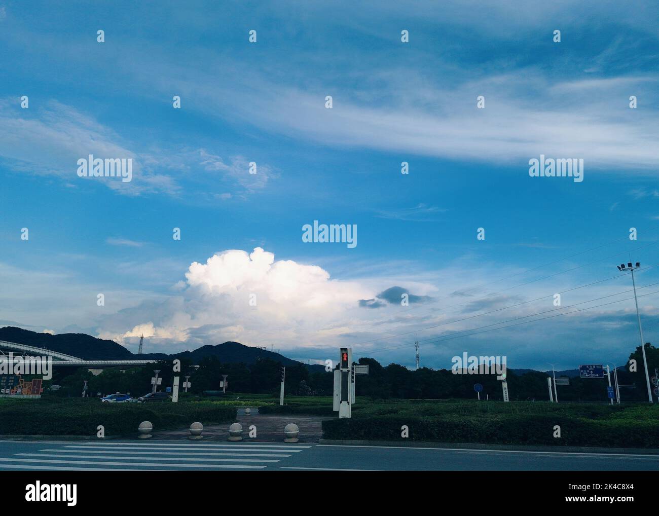A crosswalk and a street with mesmerizing clouds in sky Stock Photo