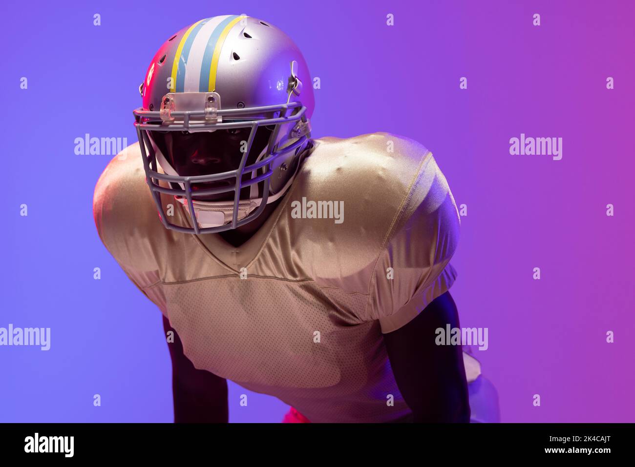 African american male american football player wearing helmet with neon blue and purple lighting. Sport, movement, training and active lifestyle conce Stock Photo