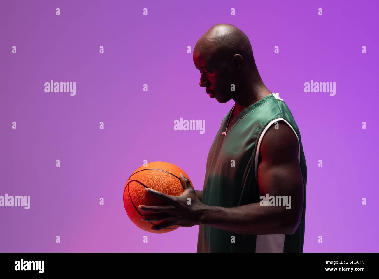 Image of african american basketball player with basketball on neon purple background. Sports and competition concept. Stock Photo