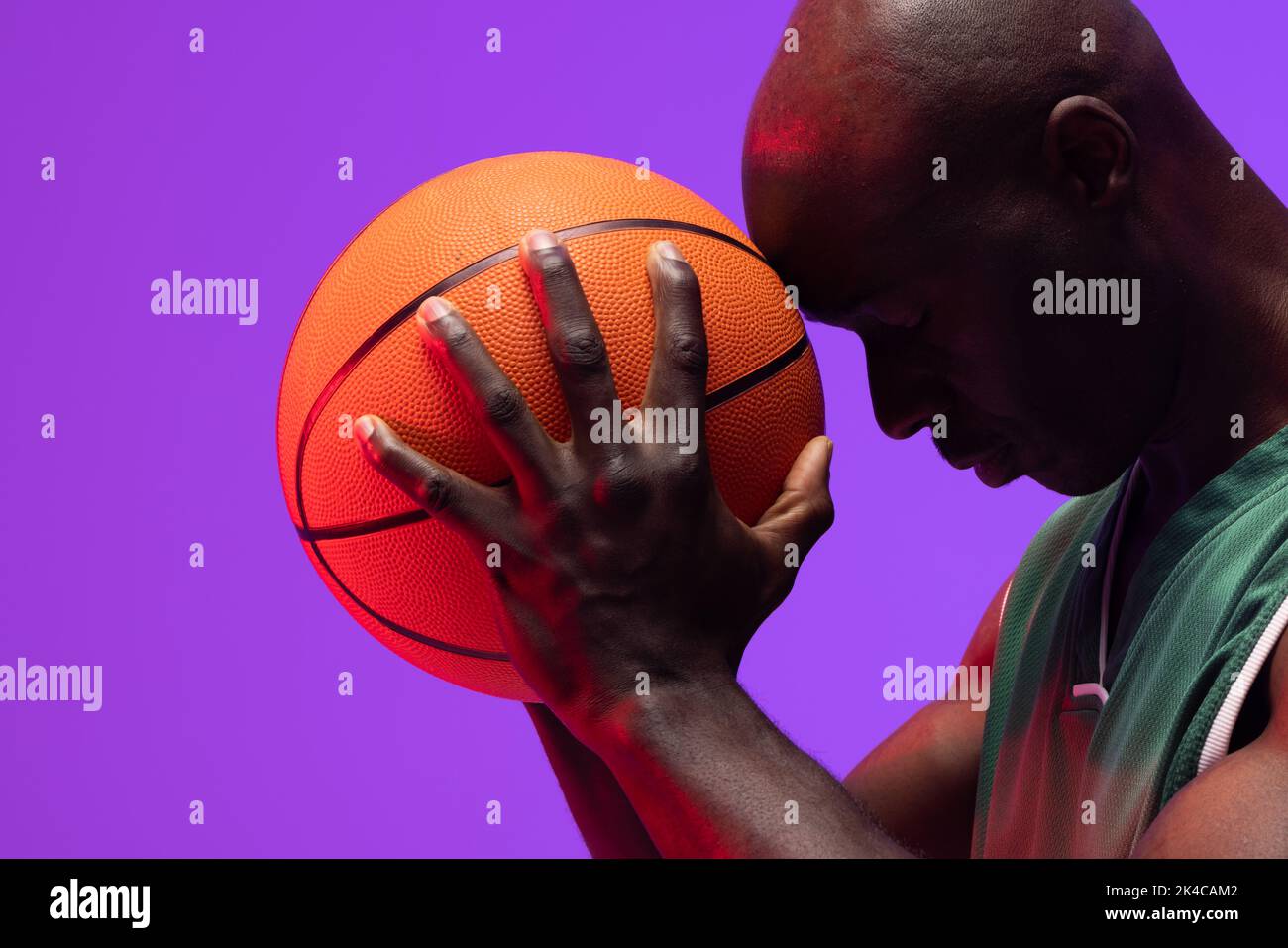 Image of african american basketball player with basketball on neon purple background. Sports and competition concept. Stock Photo