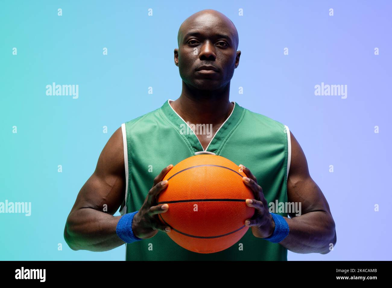 Image of african american basketball player with basketball on green to blue background. Sports and competition concept. Stock Photo