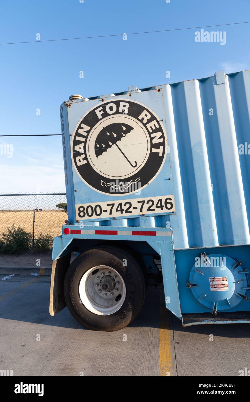 An aqua blue water tank on the back of a semi truck with a sign that reads rain for rent. Stock Photo