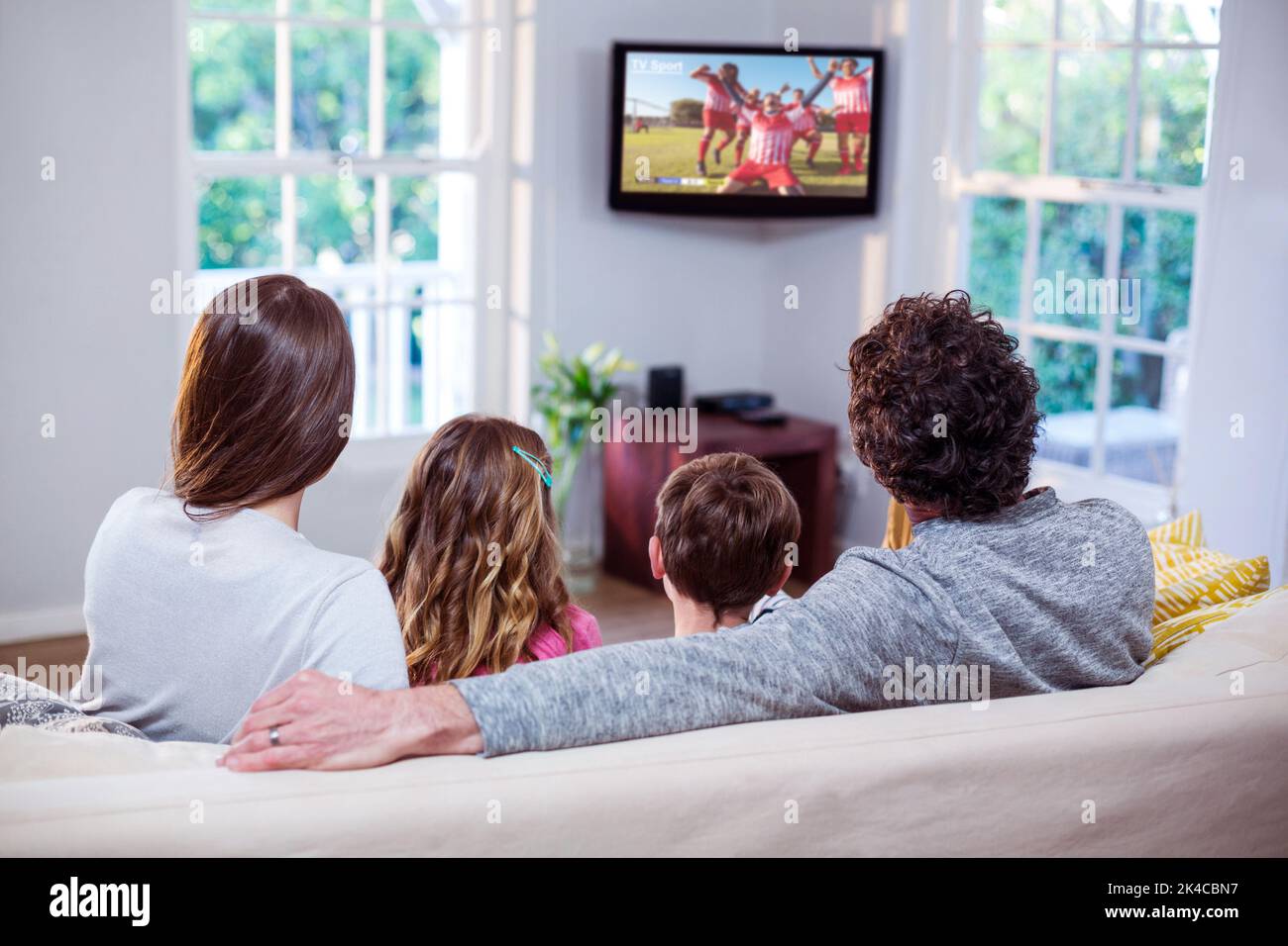 Caucasian family watching tv with football match on screen Stock Photo