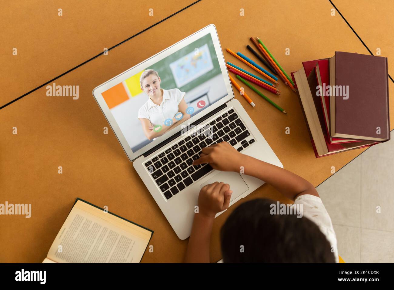Overhead view of male student having a video call with female teacher ...