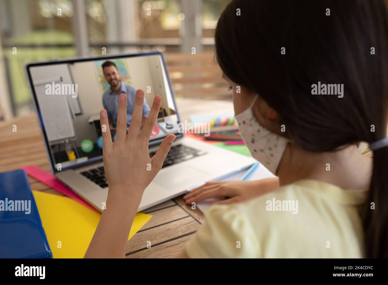Female student wearing face mask having a video call with male teacher ...