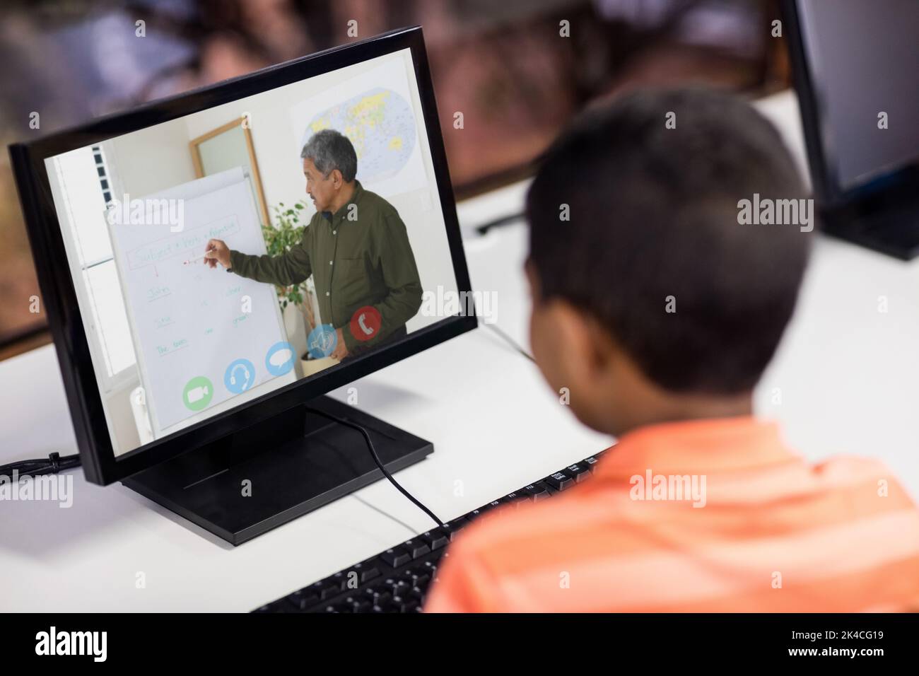 Mixed race schoolboy using computer on video call with male teacher ...