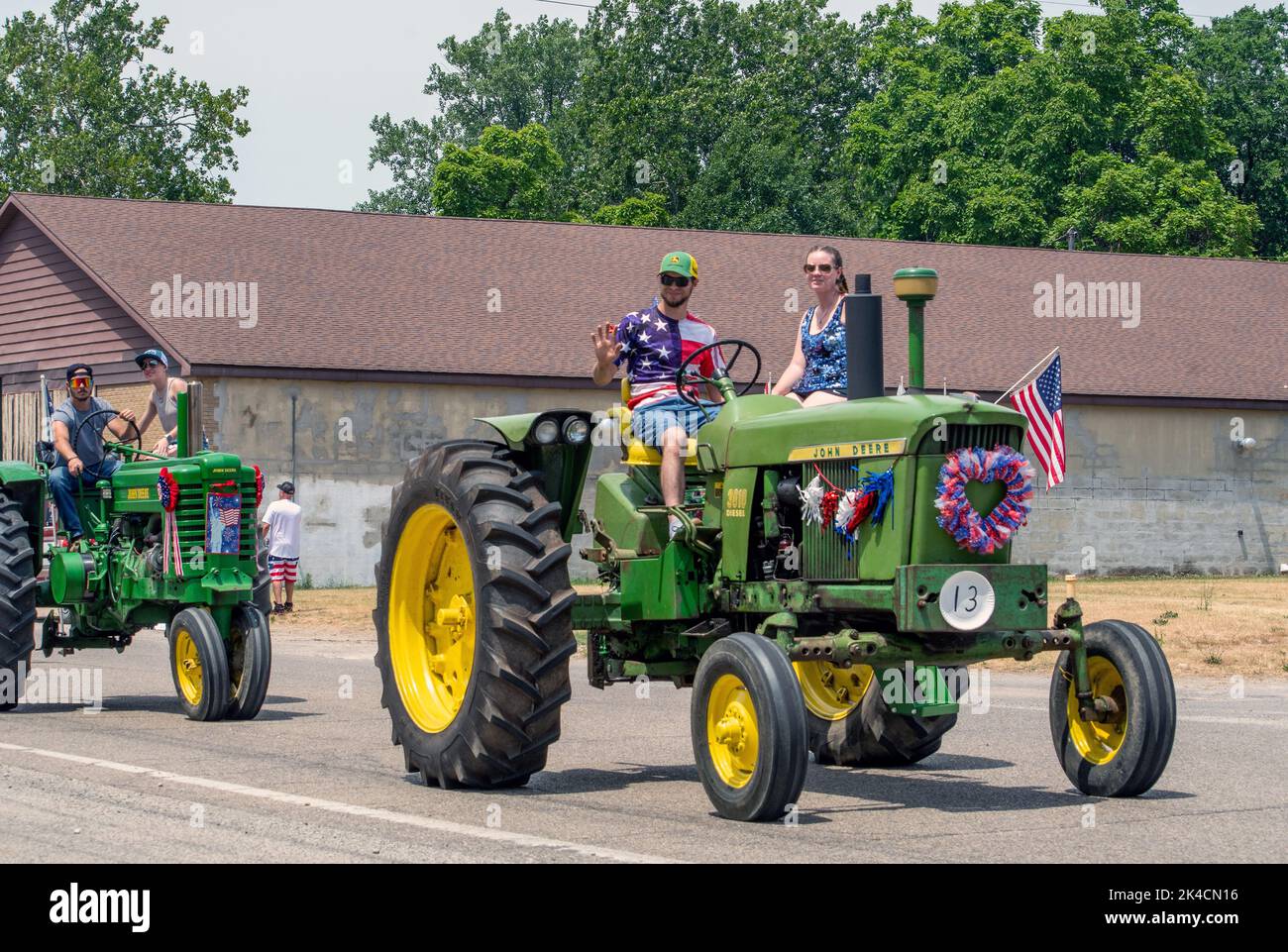 Eau Claire MI USA, July 4 2022; Young farm families drive John deere tractors in a holiday parade in small town America Stock Photo