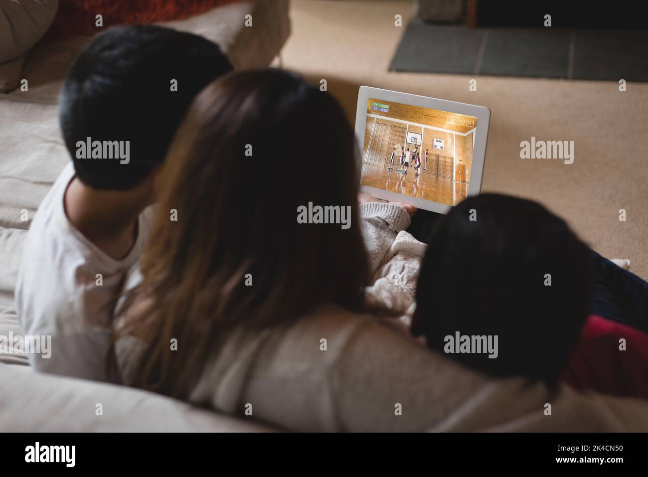 Back view of latin mother and children at home watching basketball game