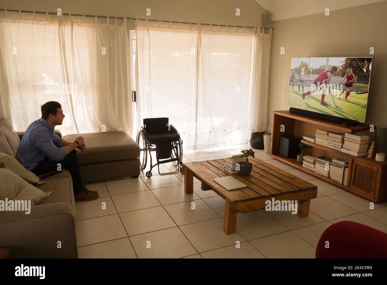 Caucasian disabled man sitting at home watching cricket match on tv. sports, competition, entertainment and technology concept digital composite image Stock Photo