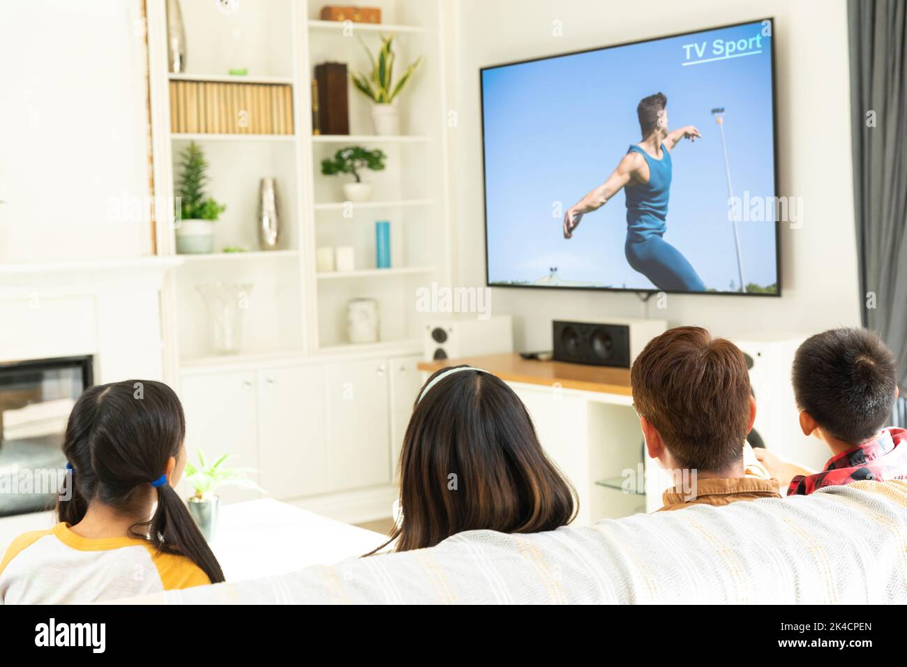 Rear view of family sitting at home together watching athletics event