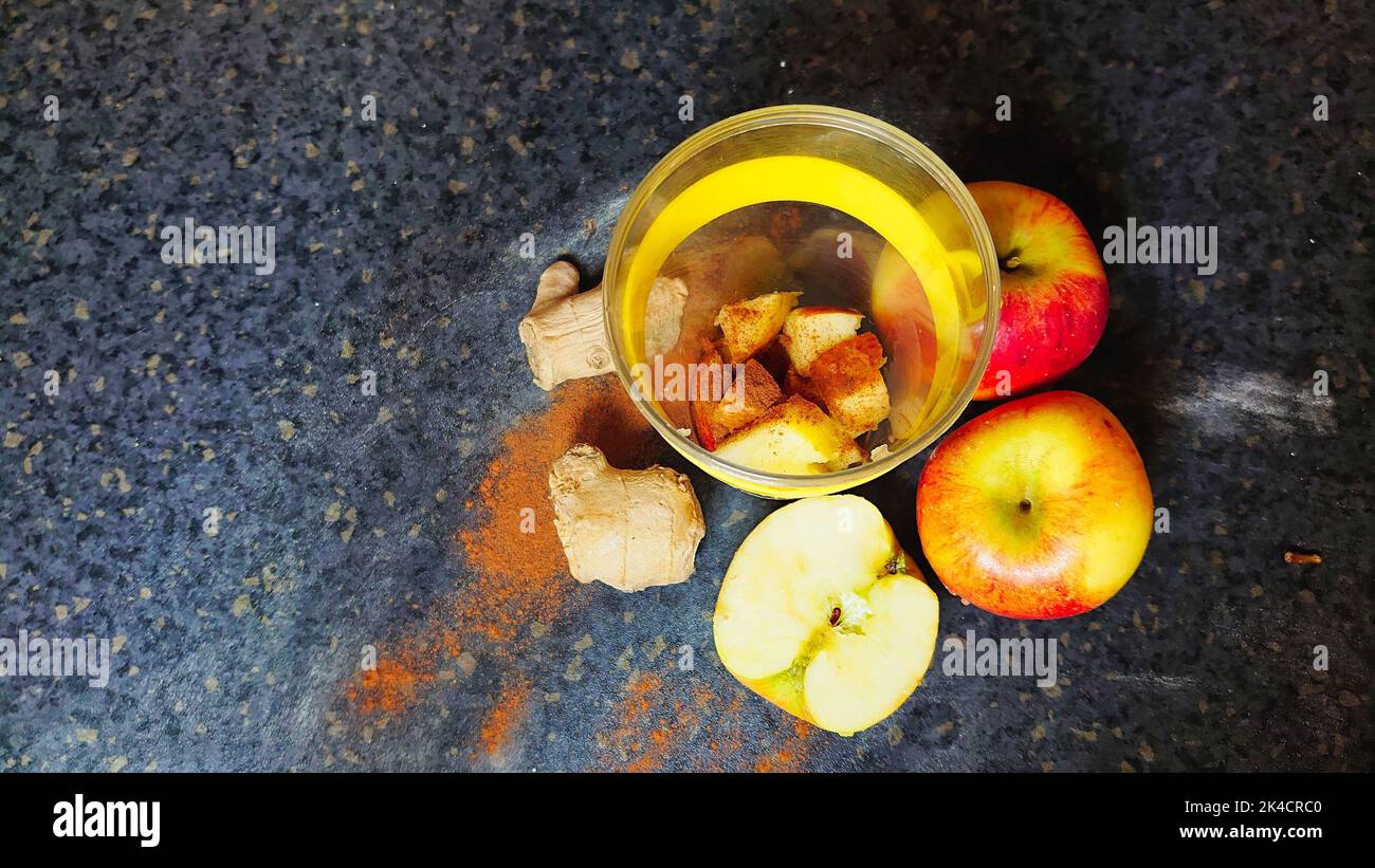 A top view of apples, ginger root, and seasoning on a kitchen table for ...