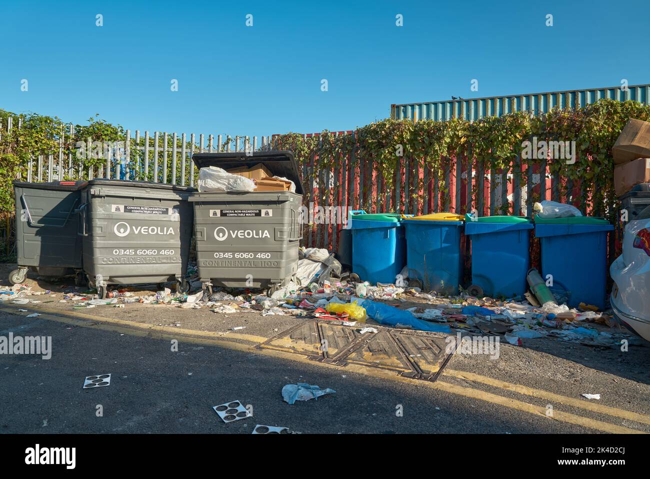 Many Wheelie bins and rubbish aligned in Margate street under blue sky