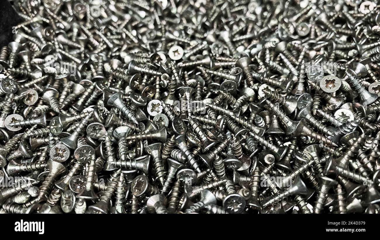 Shiny short selftapping screws closeup. Warehouse of small parts for
