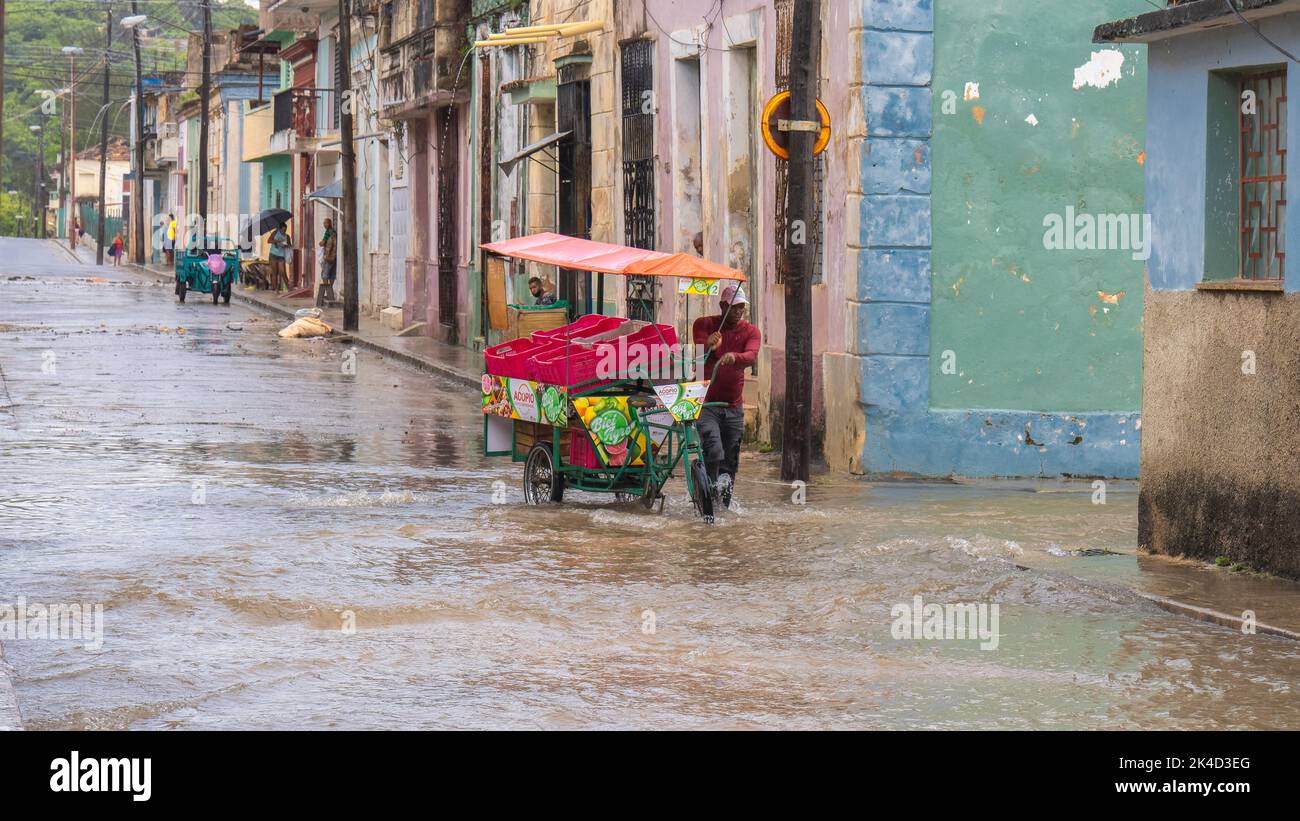 A vendor pushing his sidecar through a flooded street Stock Photo