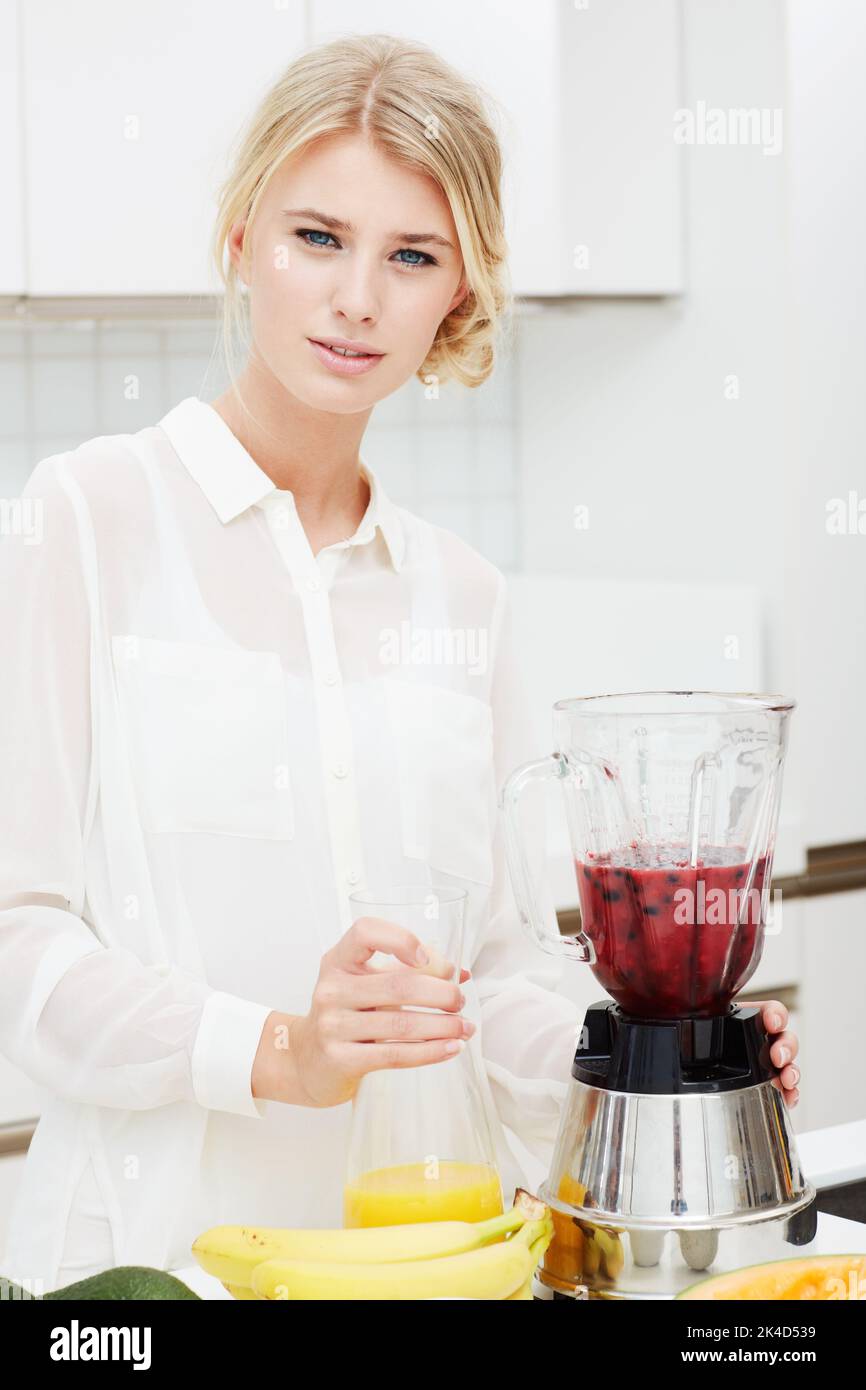 Beauty and a blender - Juicing. Portrait of a beautiful young woman making a healthy shake with her blender. Stock Photo