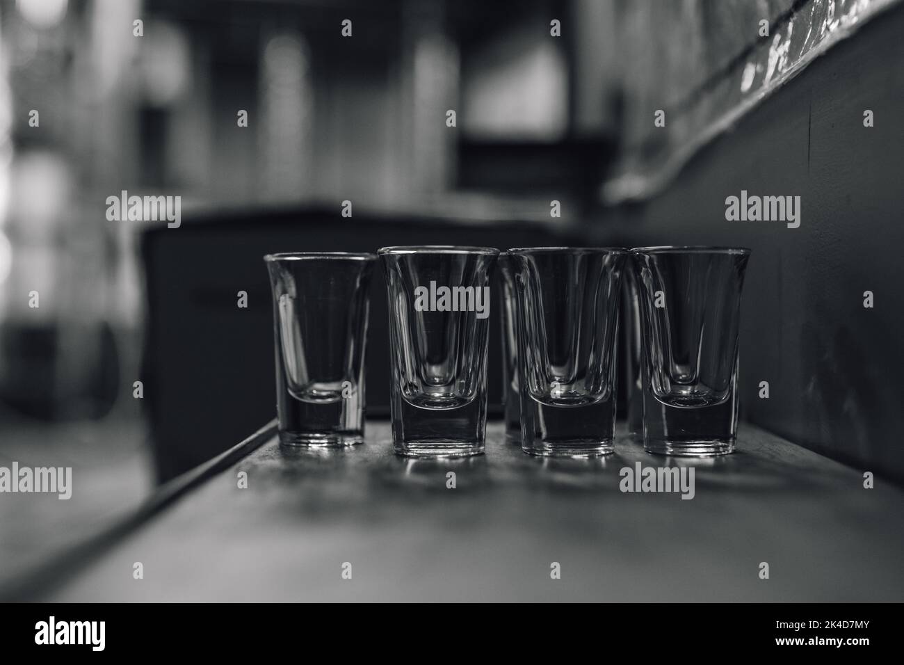 black and white image of shot glasses lined up on table, shelf ready to