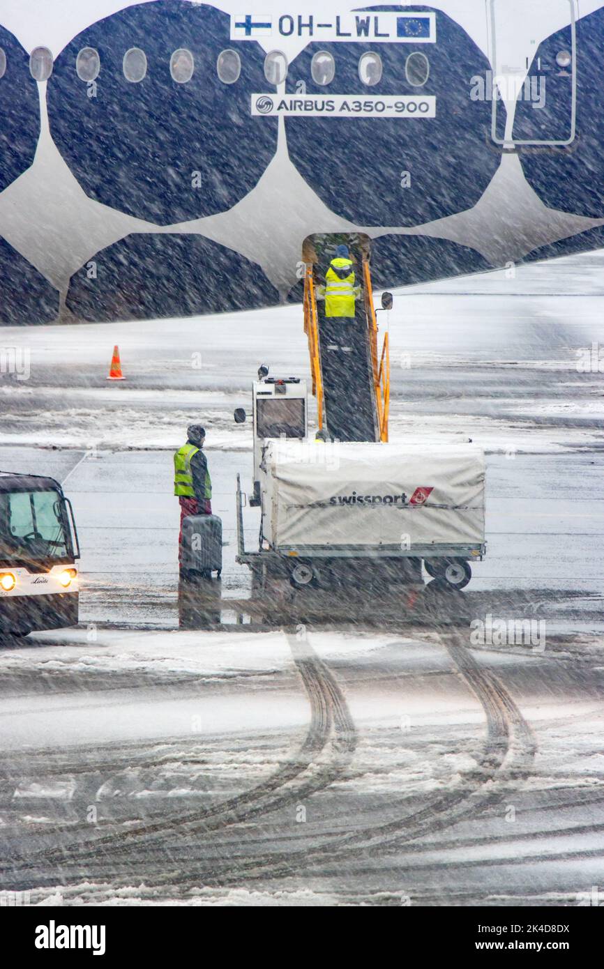 HELSINKI, FINLAND, FEB 15 2022, Loading luggage onto the plane during heavy snowfall Stock Photo