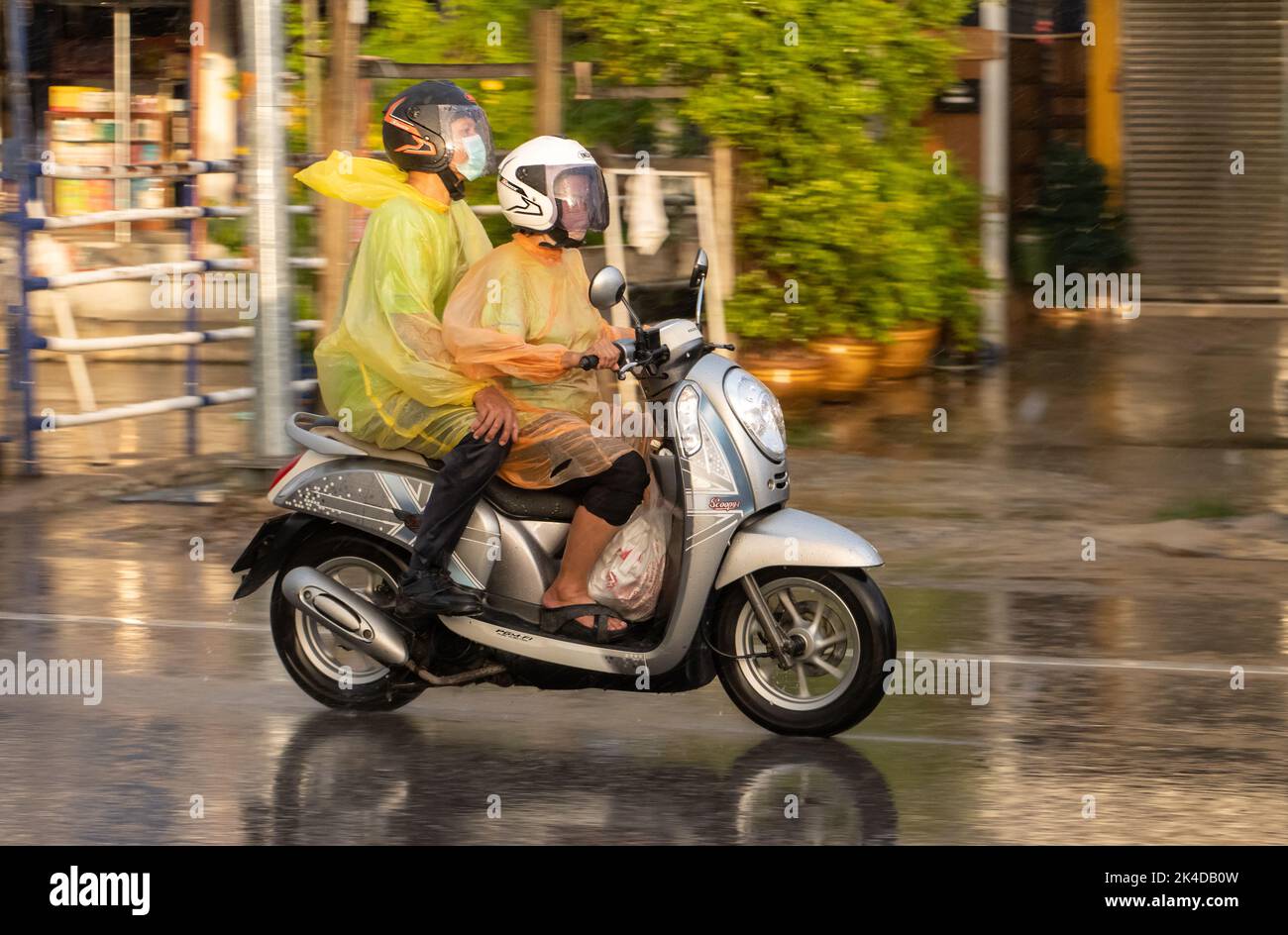 SAMUT PRAKAN, THAILAND, SEP 21 2022, Couple in raincoats drive in heavy rain Stock Photo