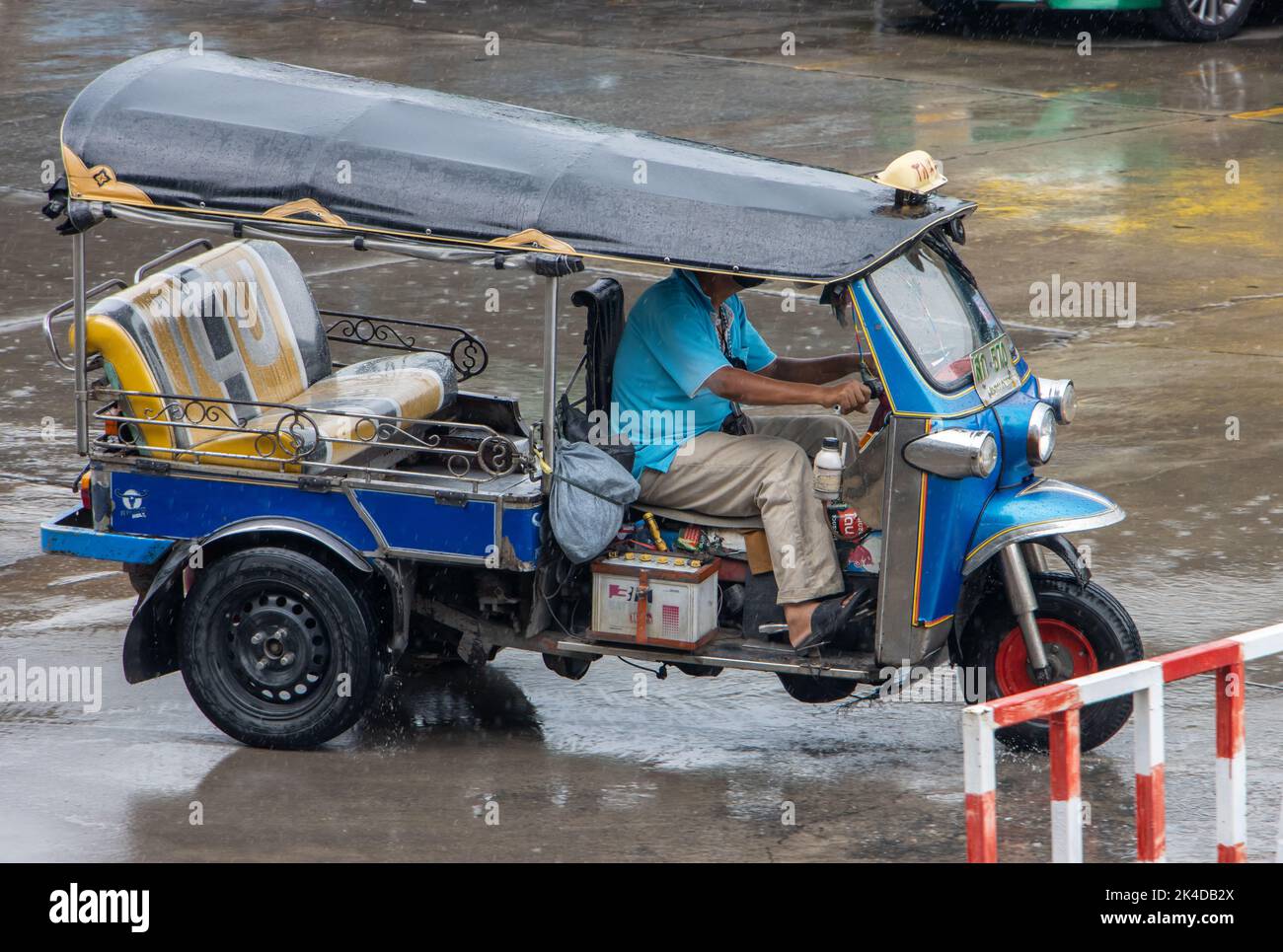 SAMUT PRAKAN, THAILAND, SEP 23 2022, An empty Tuk Tuk motor tricycle is driving a city street in the rain Stock Photo