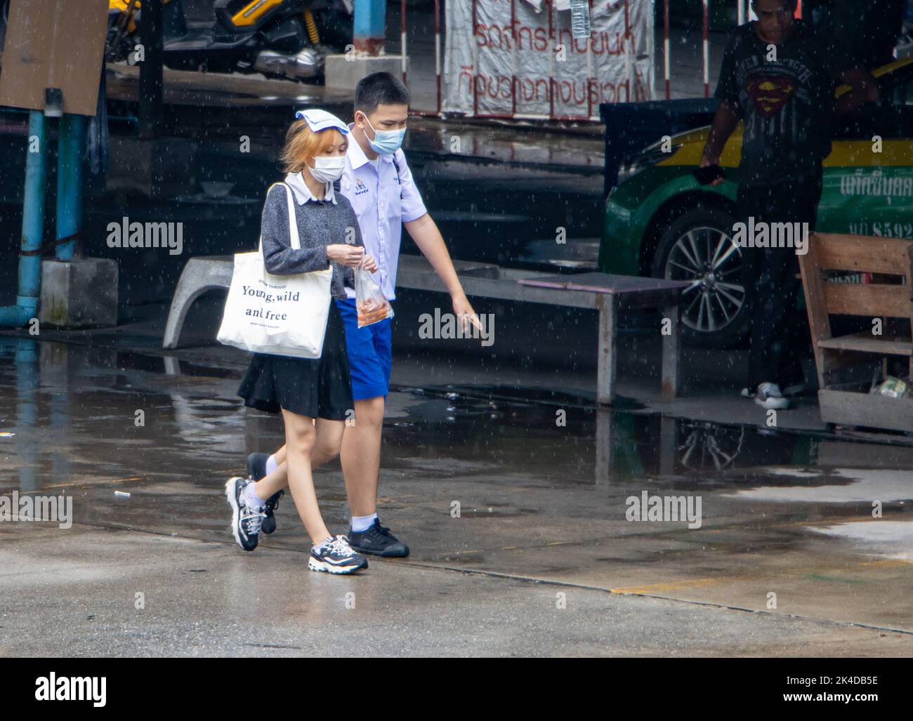 SAMUT PRAKAN, THAILAND, SEP 23 2022, A boy and a girl in school uniforms are walking on a wet street Stock Photo