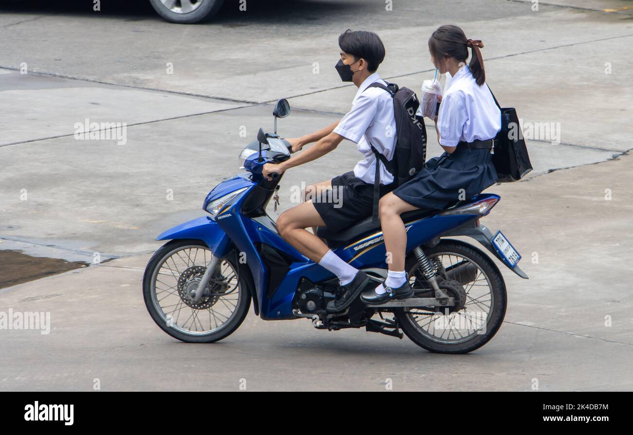 SAMUT PRAKAN, THAILAND, SEP 23 2022, A girl with a boy in school uniforms ride together on a motorcycle. Stock Photo