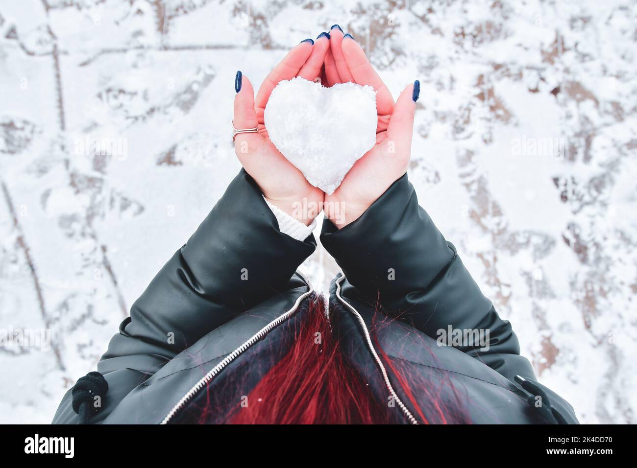 The heart made of snow in female hands. Kindness and care in snowy cold Valentin's Day. love background. kindness. Stock Photo