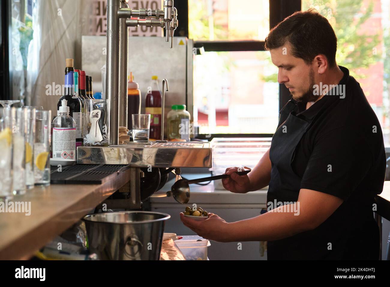 Latin waiter serving olives in a plate as an appetizer with the drinks. Stock Photo