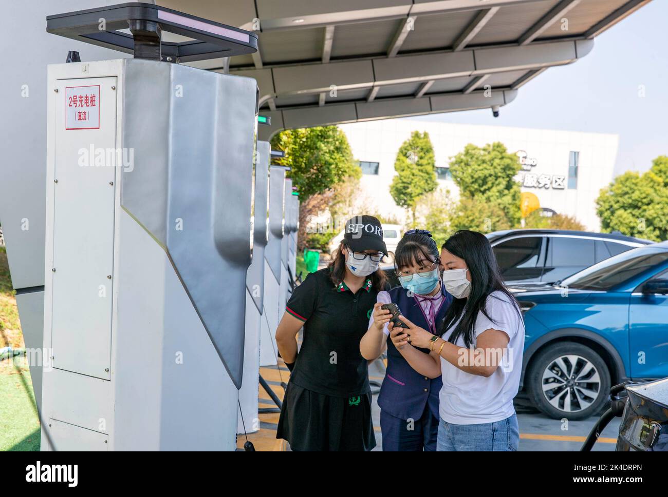 TAIZHOU, CHINA - OCTOBER 2, 2022 - A staff member assists a car owner to scan the code to charge an electric vehicle at a charging demonstration stati Stock Photo