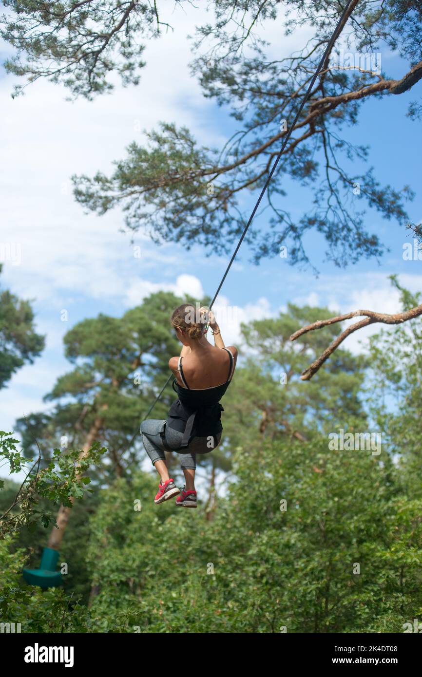 Teenage girl on a zip line in a tree climbing center Stock Photo Alamy