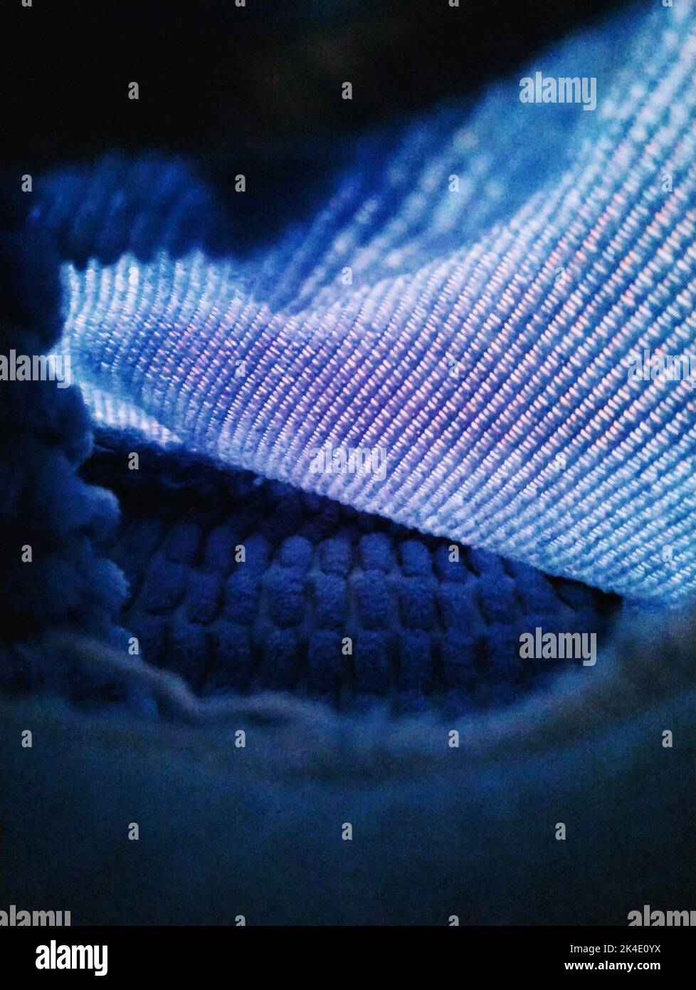 A vertical closeup of a blue knitted fabric illustrated above with blurred background Stock Photo