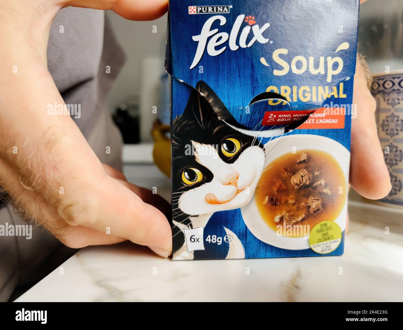 Paris, France - Sep 13, 2022: POV male hand holding carton package with pouches with Felix Soup with beef - modern kitchen background preparing to feed the pet cat animal Stock Photo