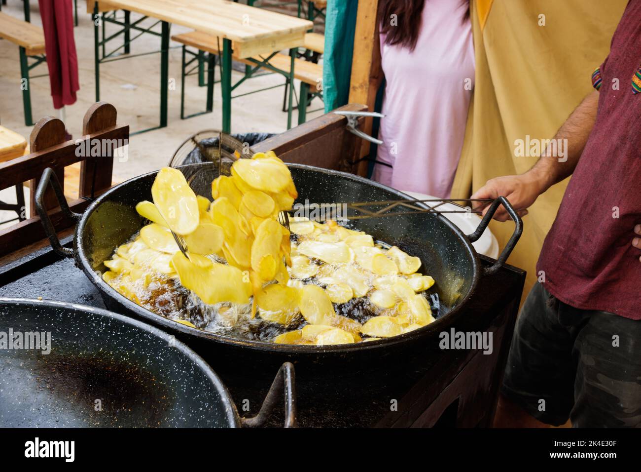 Frying sliced potatoes in oil and stirring with a slotted spoon Stock