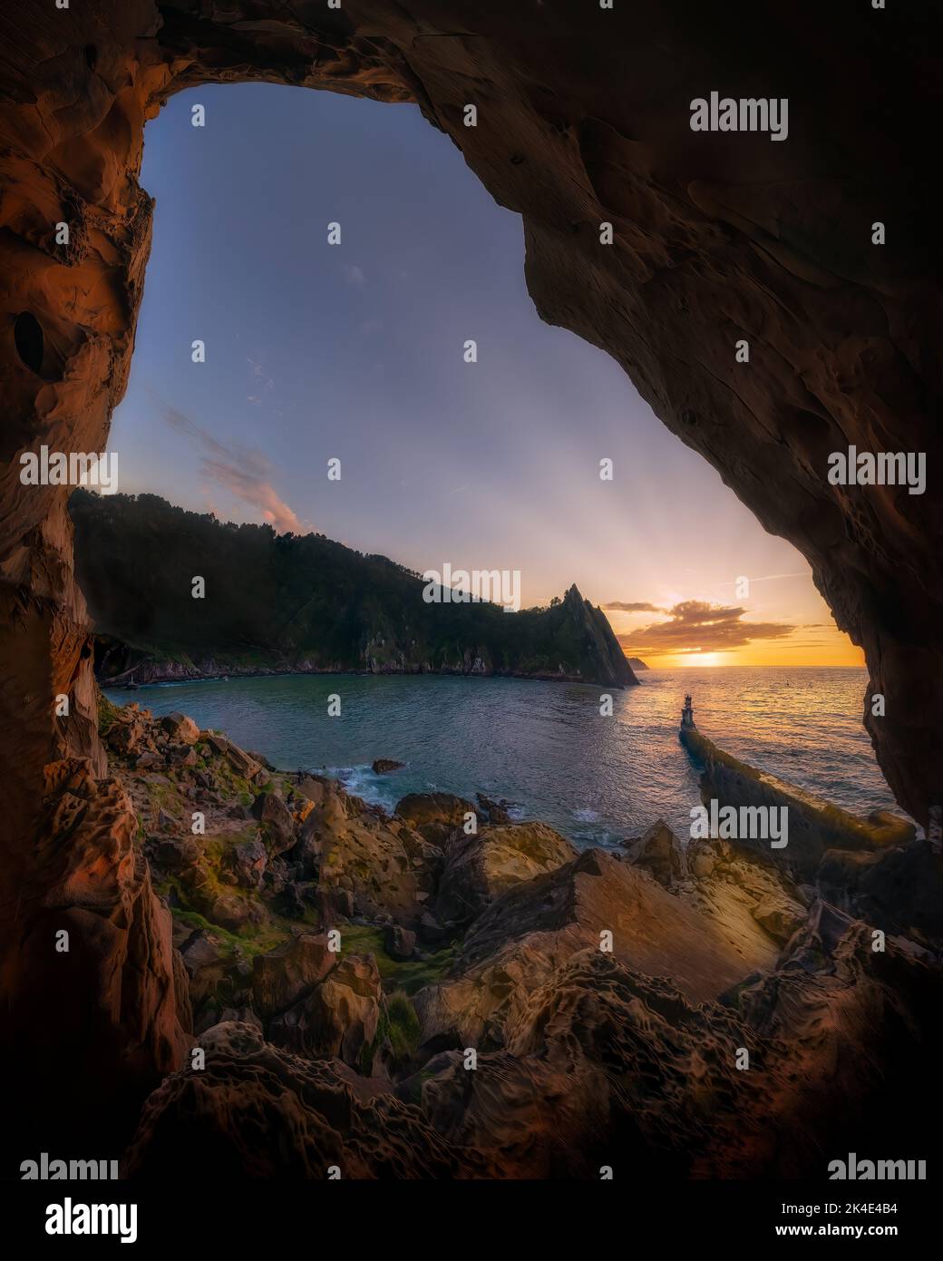 puntas de pasajes san juan donibane, desde un recoveco entre las rocas, con vistas al pequeño faro y la puesta del sol Stock Photo