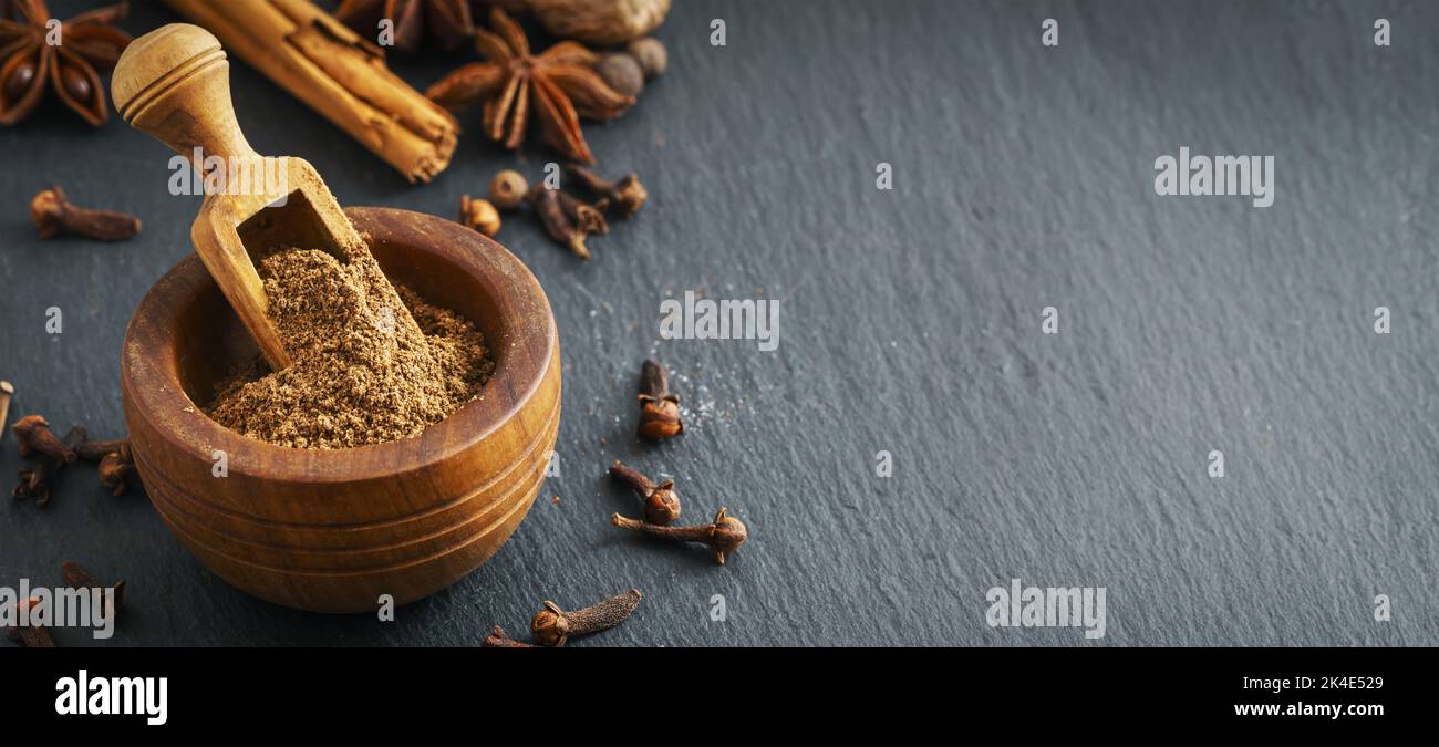 Ground cloves in wooden bowl on slate background with copy space Stock Photo