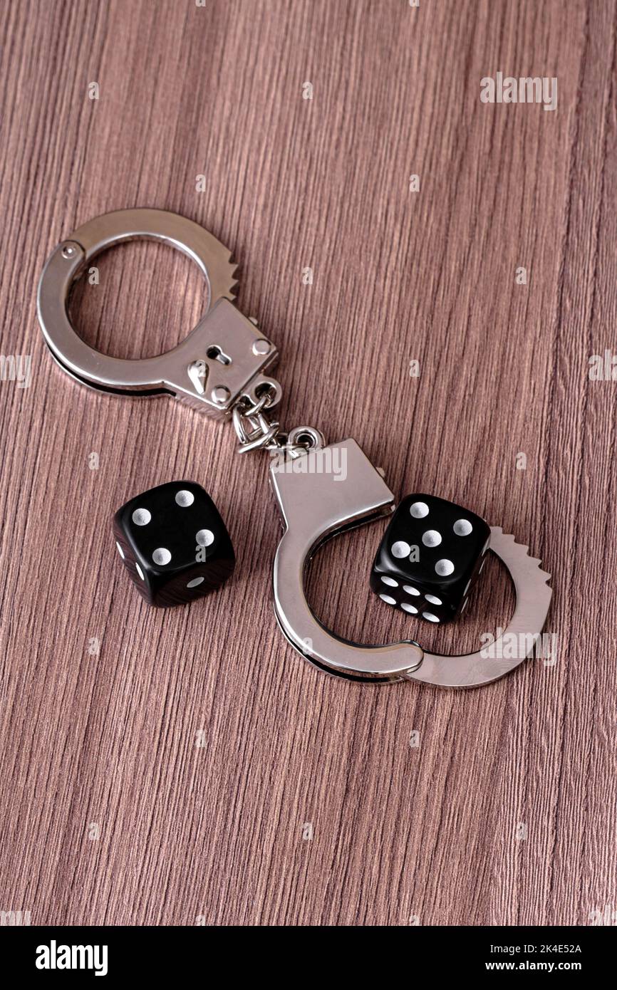Police handcuffs and two dices on table. Gambling addiction concept Stock Photo