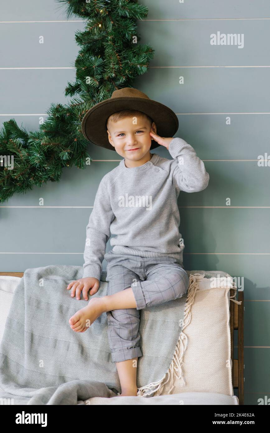 Prankster a happy child boy is sitting on the sofa in a hat that he took from his mother Stock Photo