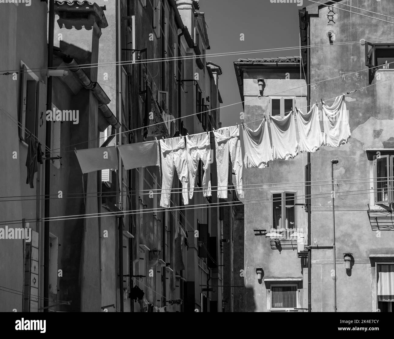 Laundry on a clothesline between houses in Italy black and white Stock Photo