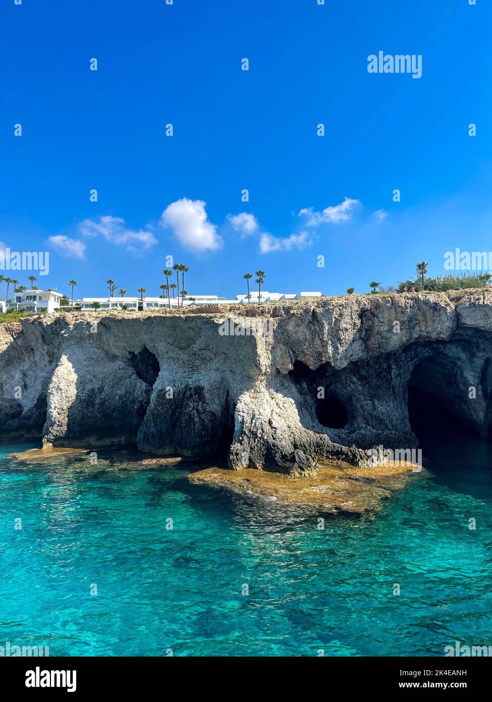 A vertical shot of rocky cliffs against a blue sea on a sunny day Stock ...