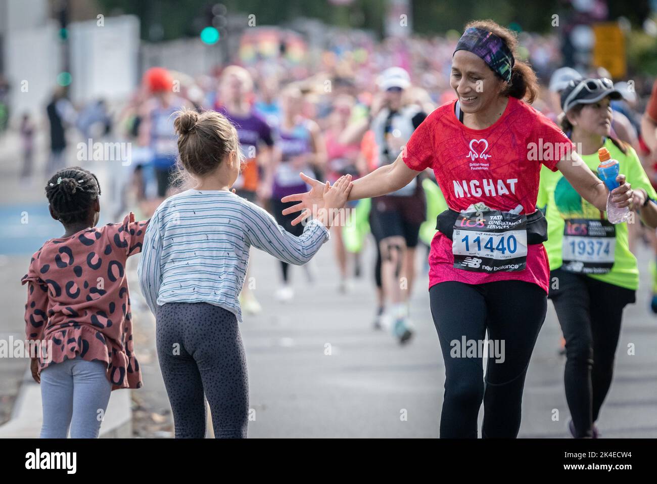 London, UK. 2nd October, 2022. Local children give 'high-fives' as London Marathon passes down Deptford’s Evelyn Street in South East London, the 8 mile mark of the 26.2 mile course where runners are greeted and cheered on by local residents. Credit: Guy Corbishley/Alamy Live News Stock Photo