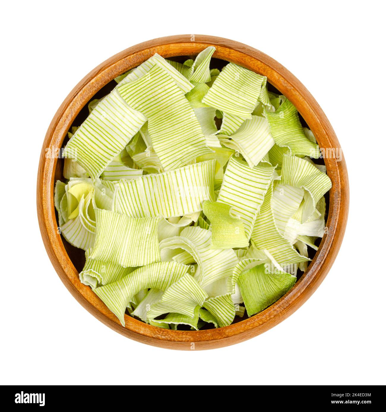 Dehydrated leek flakes, from above, in a wooden bowl. Dried strips of Allium porrum, a slightly green, crunchy and firm vegetable, with aromatic taste. Stock Photo