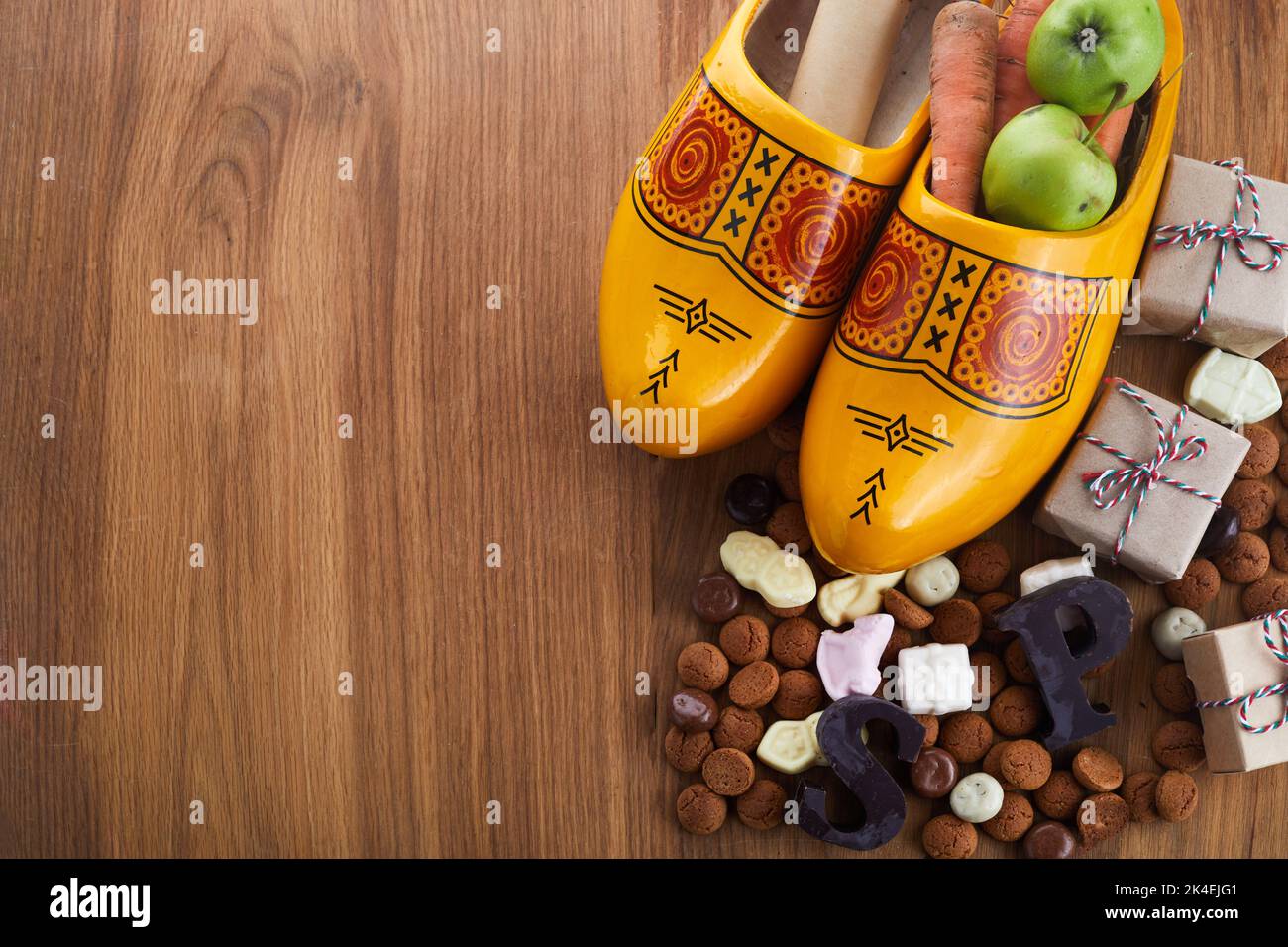 Saint Nicholas - Sinterklaas day with shoe, carrot and traditional sweets on wooden background Stock Photo