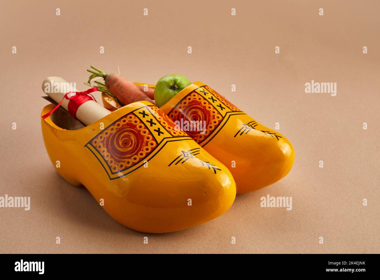 Saint Nicholas - Sinterklaas day with shoe, carrot and apples on caramel background Stock Photo