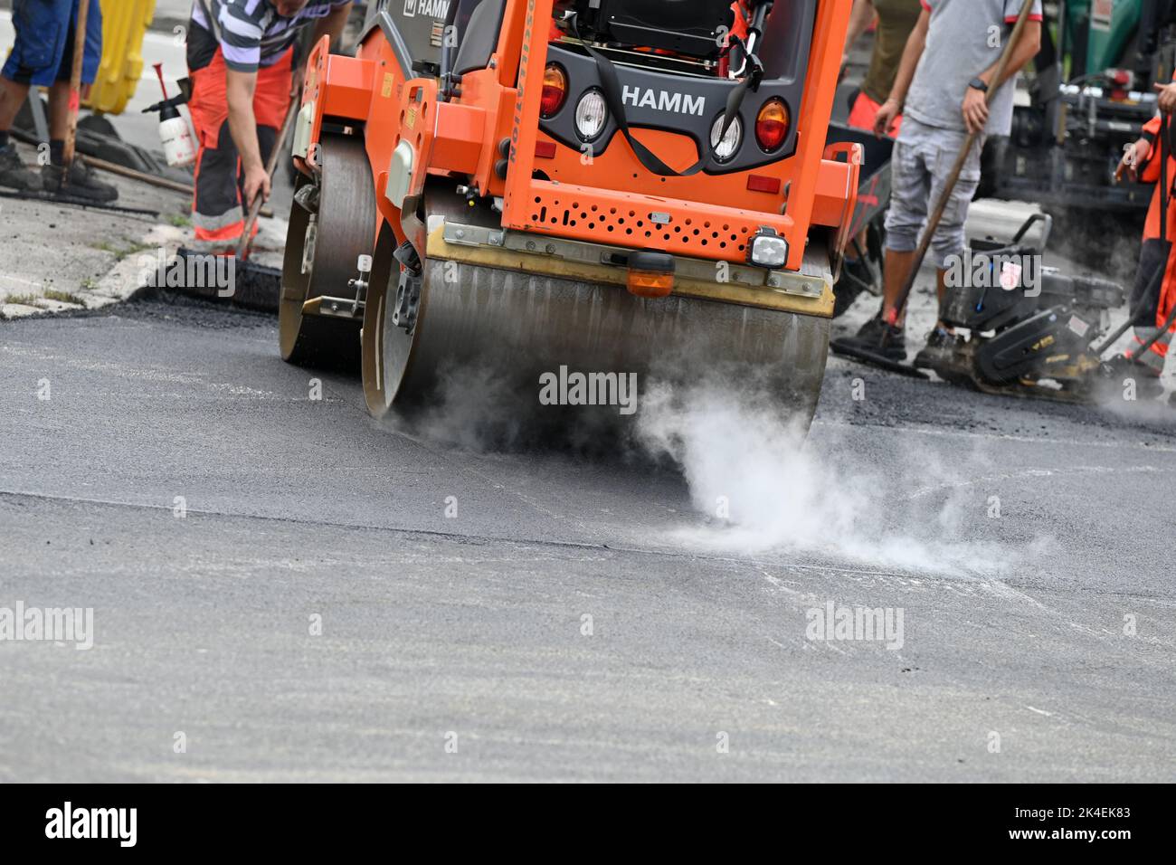 A road roller compacts asphalt at a road construction site Stock Photo