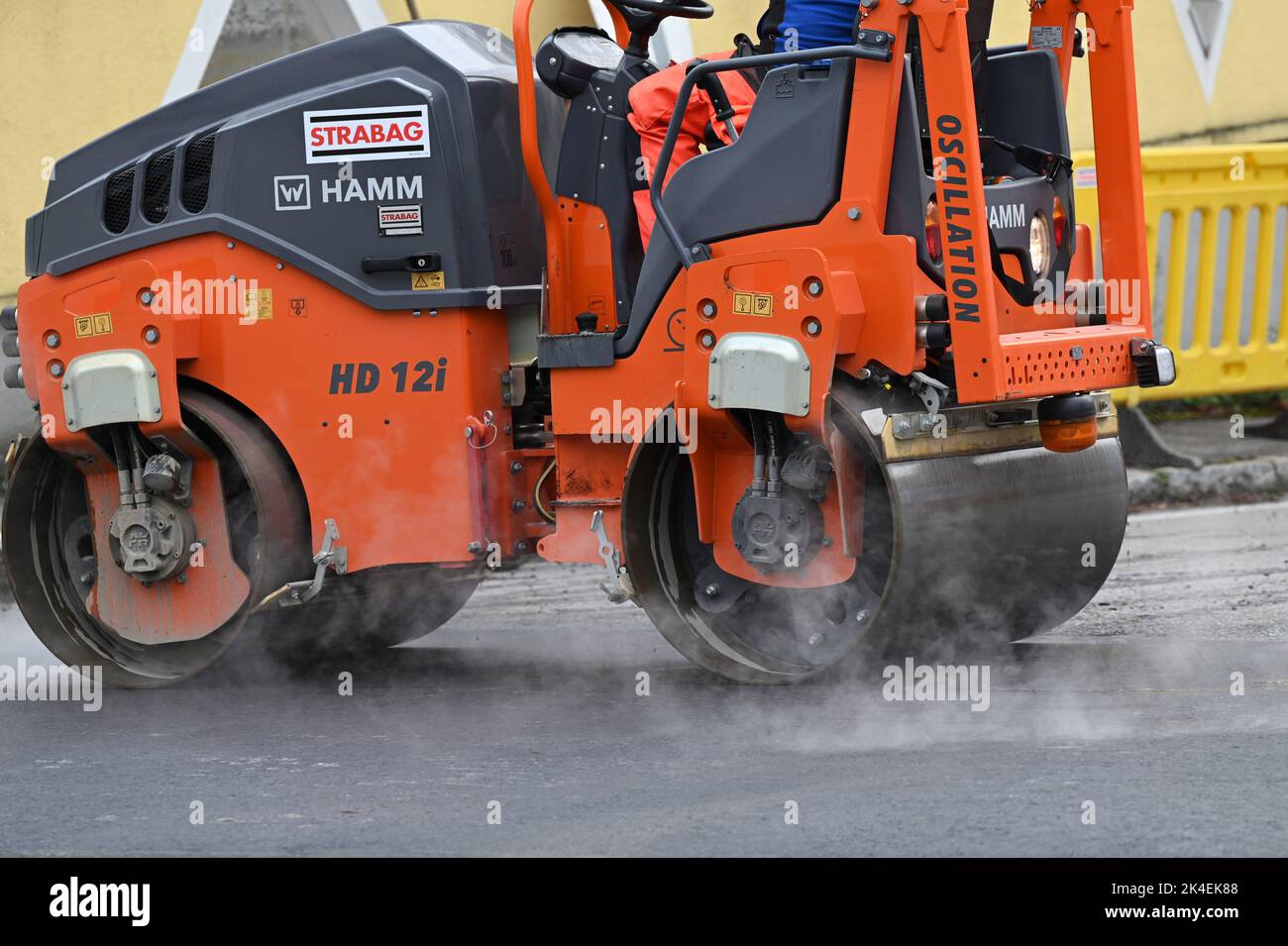 A road roller compacts asphalt at a road construction site Stock Photo