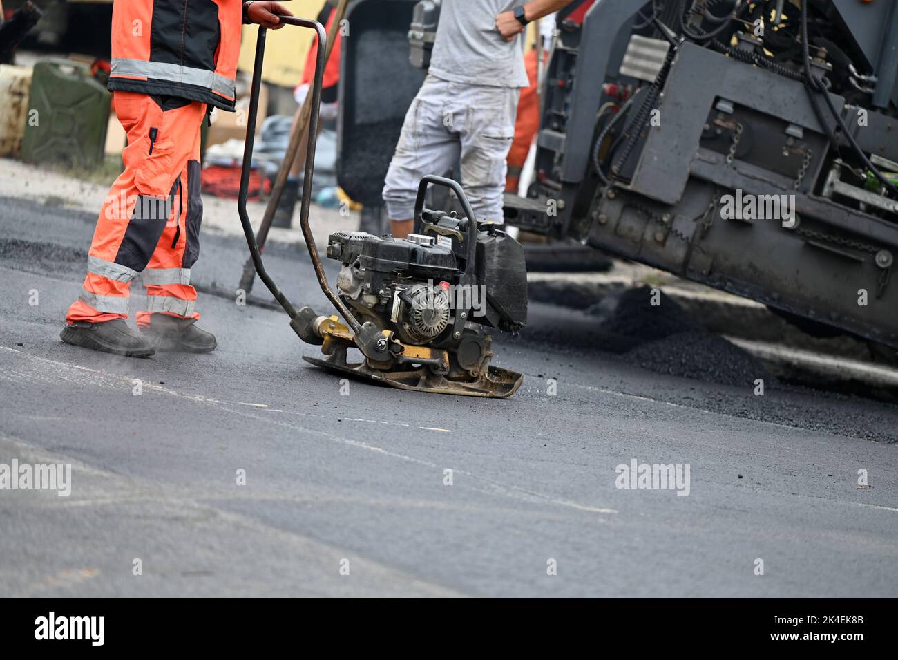 A plate compactor for compacting asphalt at a road construction site Stock Photo