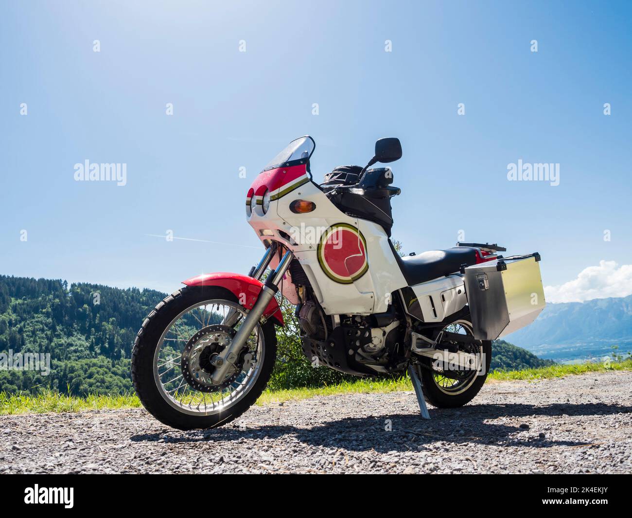 An adventure motorcycle with big aluminum cases is parked at a mountain pass in the Swiss alps. Stock Photo
