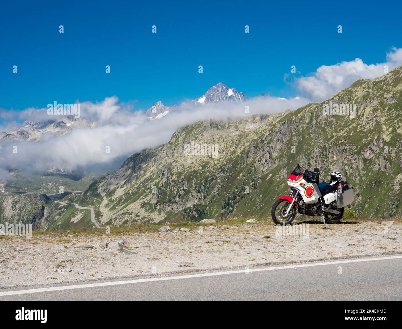 An adventure motorcycle with is parked at a mountain pass in the Swiss alps. Stock Photo